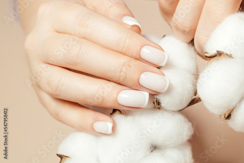 Delicate manicure on a beige background with cotton.