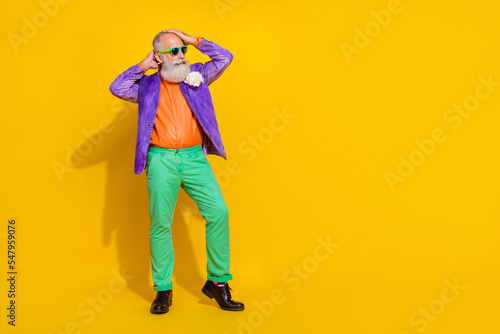 Full length photo of cool positive guy dressed violet velvet jacket looking empty space isolated yellow color background