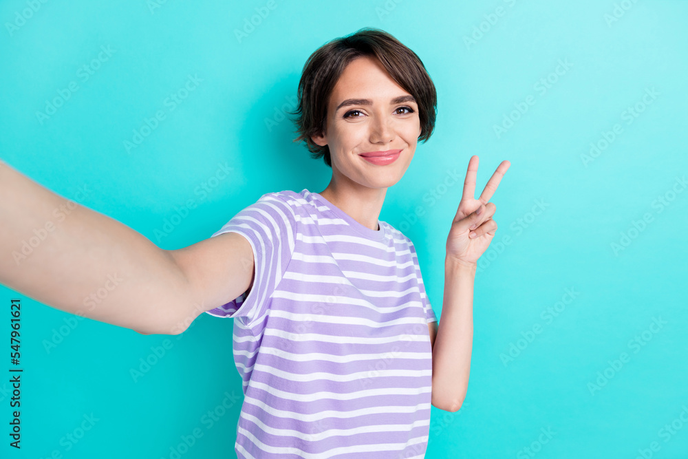 Portrait of nice pretty good mood girl with bob hairdo wear striped t-shirt showing v-sign doing selfie isolated on teal color background Portrait of nice pretty good mood girl with bob hairdo wear striped t-shirt showing v-sign doing selfie isolated on teal color background
