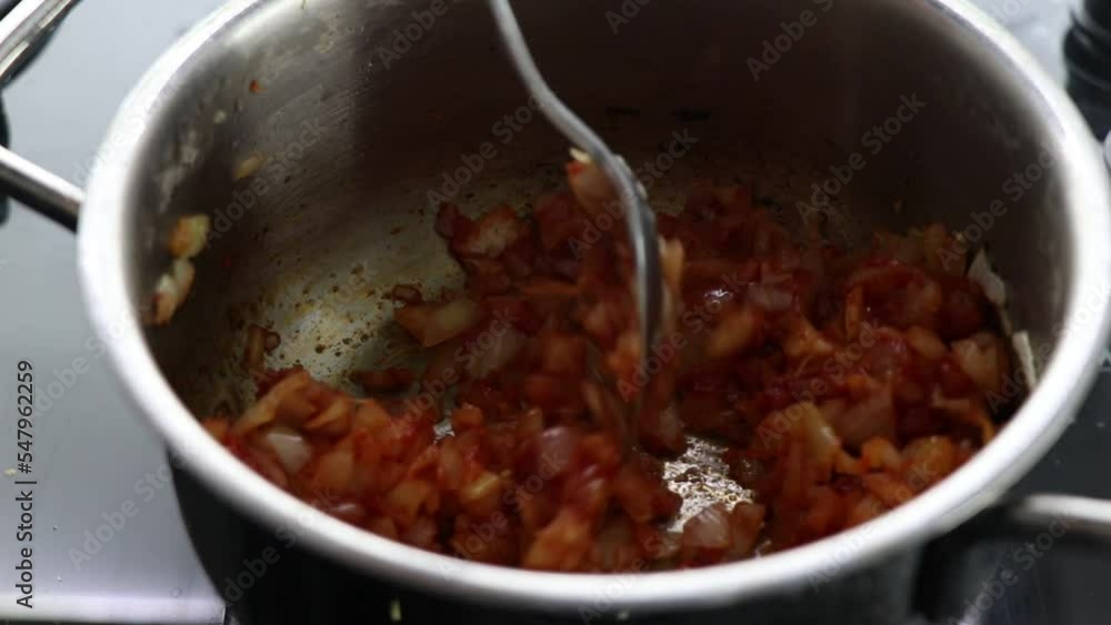 Adding water to the onion and tomato paste sauce fried with oil in a metal pot in the kitchen Adding water to the onion and tomato paste sauce fried with oil in a metal pot in the kitchen