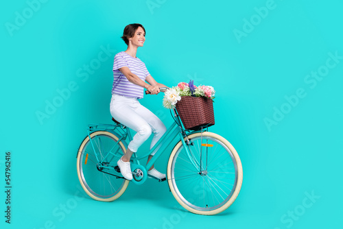 Full length photo of shiny charming lady wear violet t-shirt looking empty space cycling isolated turquoise color background © deagreez