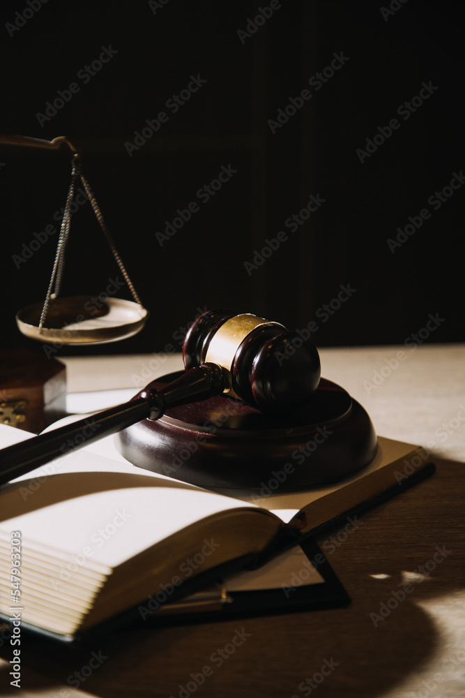 Justice and law concept.Male judge in a courtroom with the gavel, working with, computer and docking keyboard, eyeglasses, on table in morning light Justice and law concept.Male judge in a courtroom with the gavel, working with, computer and docking keyboard, eyeglasses, on table in morning light