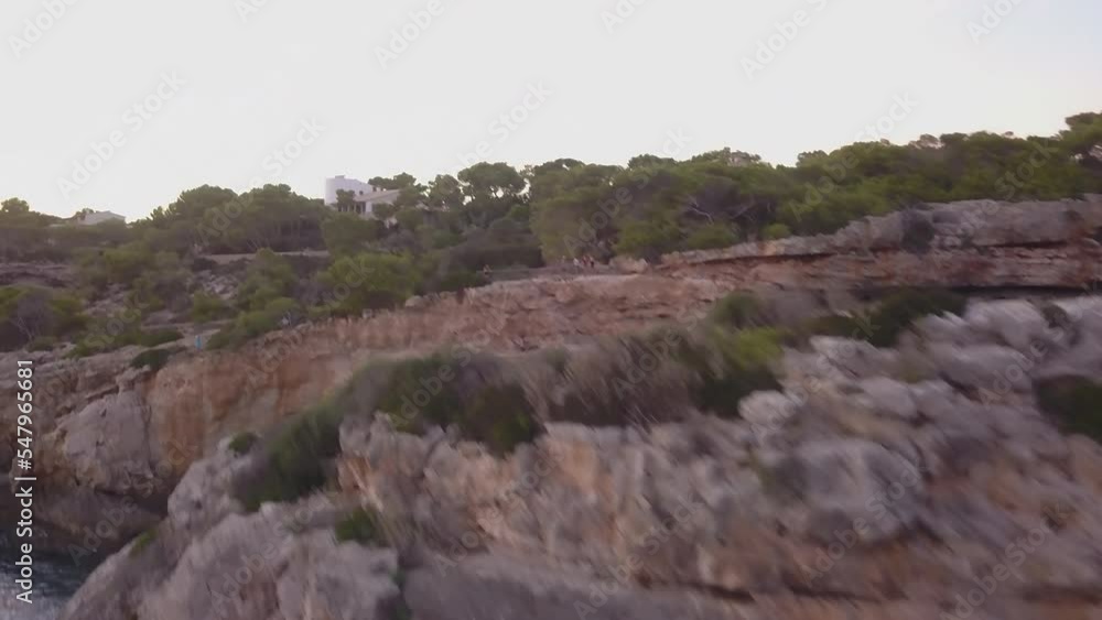 View of an arched rock and houses between pines and mountains View of an arched rock and houses between pines and mountains