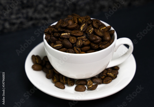 Natural coffee beans in a white cup on the table. Coffee day. Close-up. Selective focus.