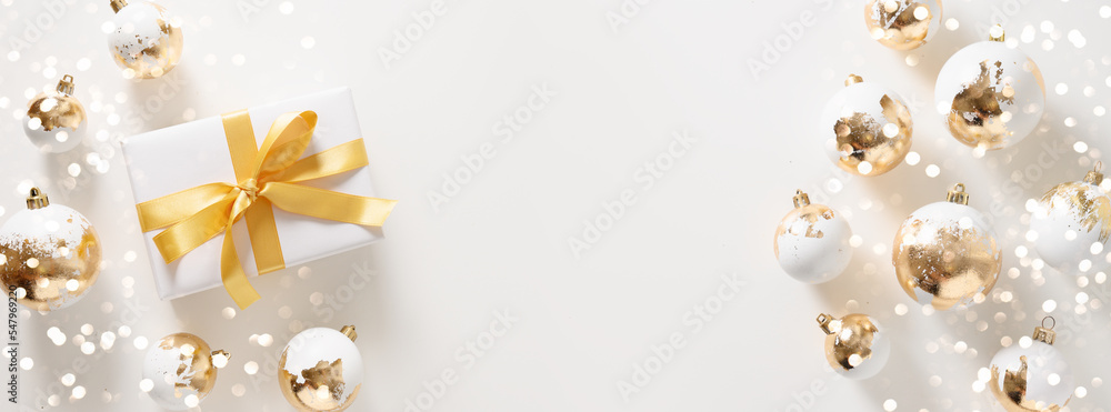 Fototapeta premium Beautiful Christmas banner with white gift , golden balls and bokeh on white background. Xmas greeting card with copy space. Modern luxury Christmas card. Happy New Year.