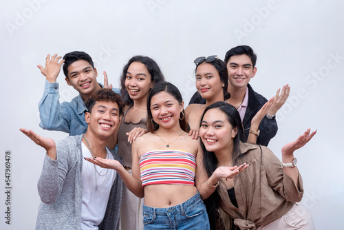 A group of seven close friends in their late teens to early 20s looking at the camera, smiling. Teamwork and unity concept. Isolated on a white backdrop.