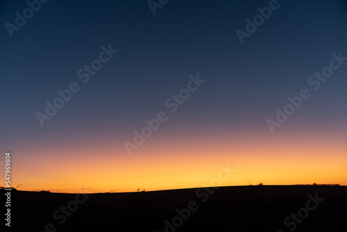 Background with landscape of an amazing and illuminated orange sunset in the blue sky, with a black base