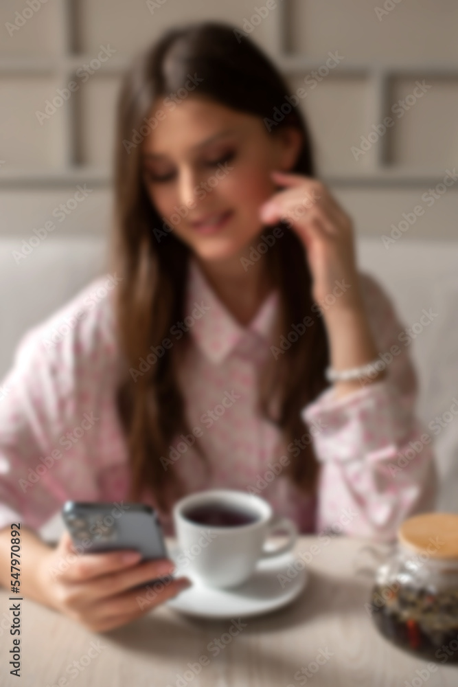 defocused and blurry woman drink tea in cafe searching for information in phone in lunch time. vertical photo defocused and blurry woman drink tea in cafe searching for information in phone in lunch time. vertical photo
