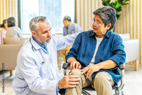 Orthopedist examines the knee of elderly patient to collect information for physical therapy treated. Doctor touch knee pain area of Old woman legs talking about knee pain symptom.