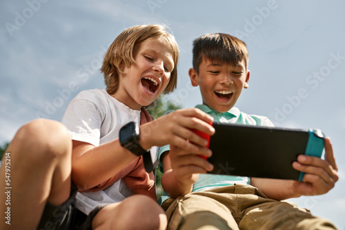 Obraz na płótnie Boy look at friend play video game on game console