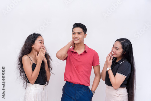 A young man feeling handsome and full of himself after getting the attention of two enamored women. Isolated on a white background. photo