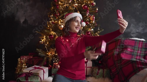 White woman in red sweater holds smart phone make video call on Christmas Eve 