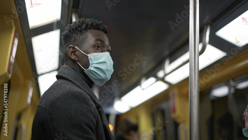 Man holding subway handrail standing at metro wearing coronavirus covid face mask
