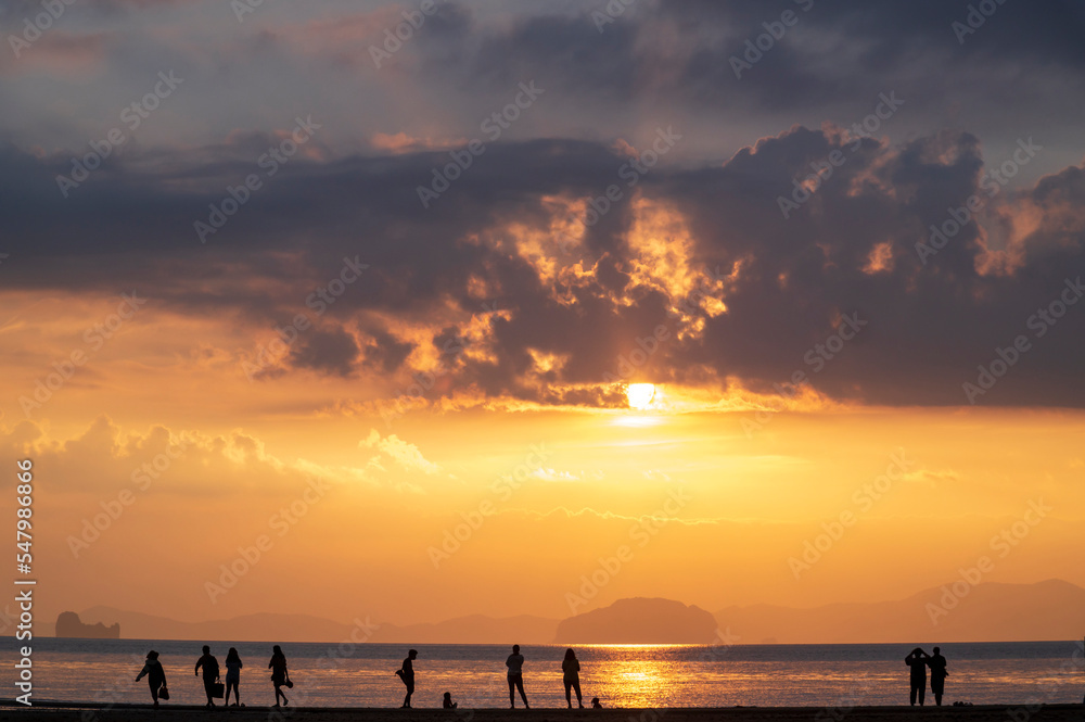 tourist watching sunset or sunrise  on beach with seascape and gold lighting sunset sky background