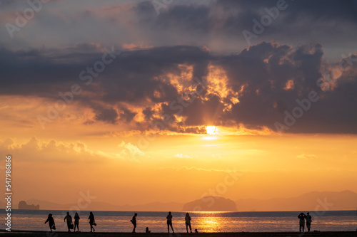 tourist watching sunset or sunrise on beach with seascape and gold lighting sunset sky background