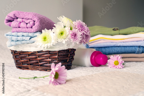 Stack of clean  colorful clothes and flowers on the bed