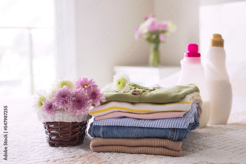 Stack of clean, colorful clothes and flowers on the bed Stack of clean, colorful clothes and flowers on the bed