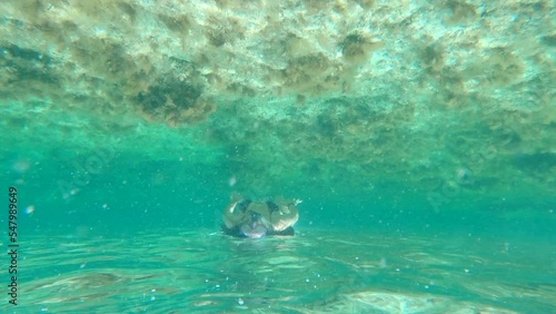 Upside down view of a girl snorkeling in a shallow beach approaching to camera.  photo