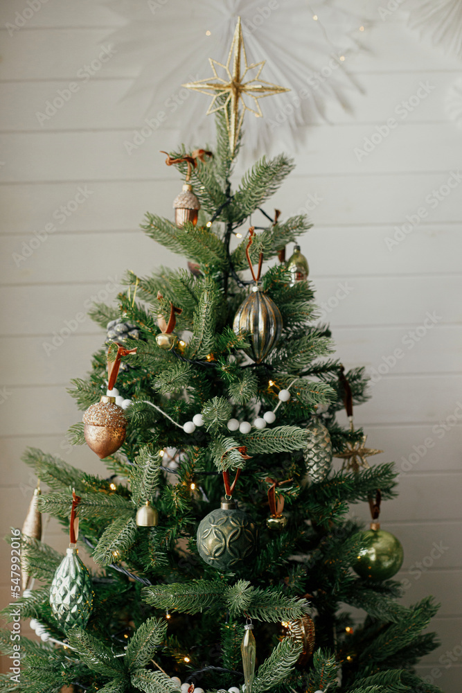 Stylish christmas tree with vintage baubles and golden lights. Modern
