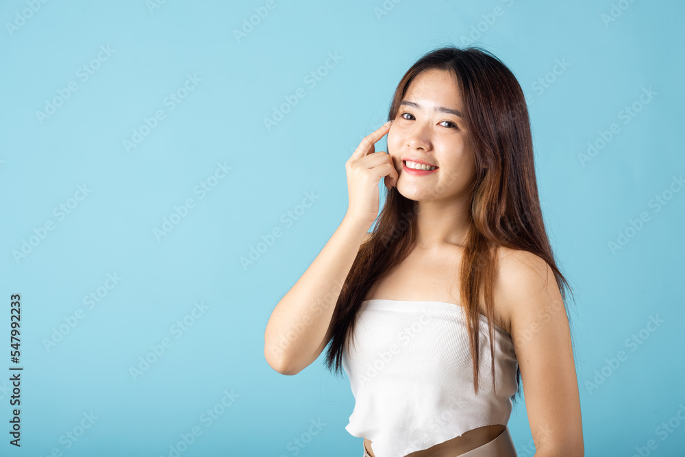 Close up woman smiling with natural makeup and healthy face, Asian young female with beauty face touching healthy facial skin studio shot isolated on blue background, Skin care and Beauty concept Close up woman smiling with natural makeup and healthy face, Asian young female with beauty face touching healthy facial skin studio shot isolated on blue background, Skin care and Beauty concept