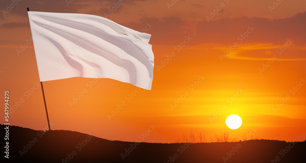 White flag waving in the wind on flagpole against the sunset sky with