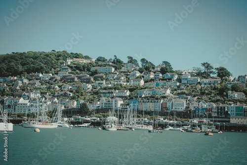 Waterside view of boats docked at the coast of Dartmouth town before the blue skyline