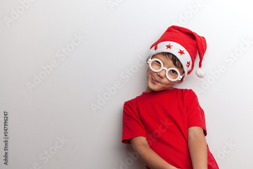A child in Santa's red hat and white funny glasses on a white background. Studio. 