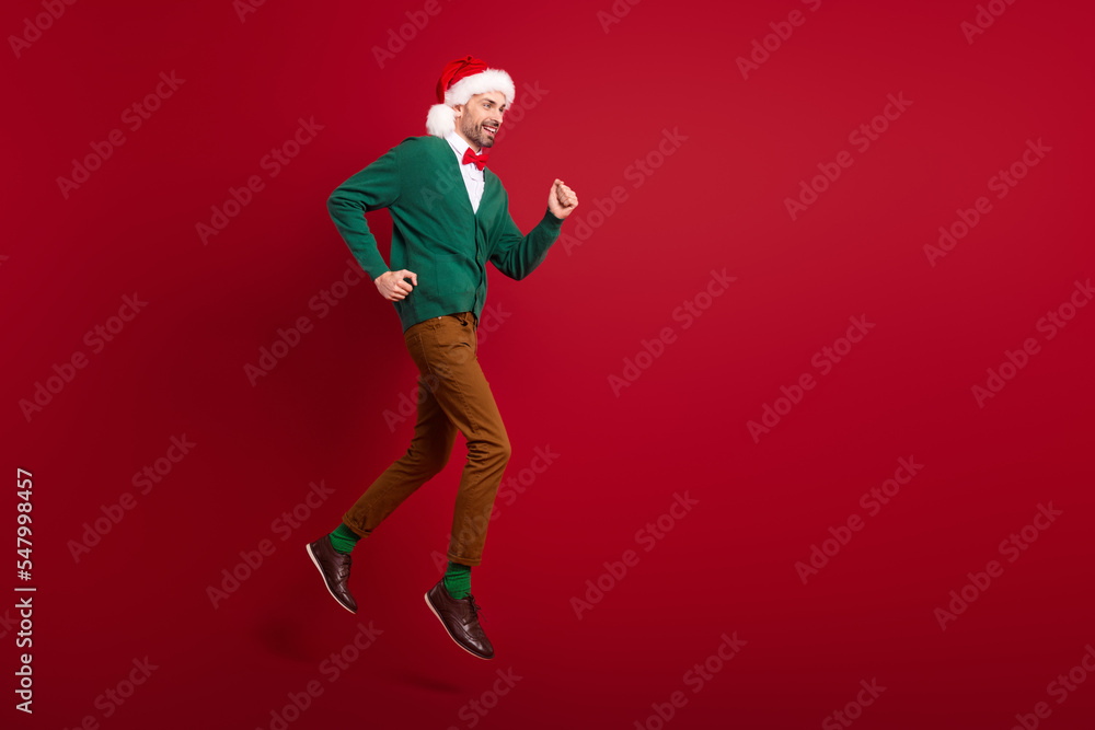Full length profile portrait of energetic active guy jumping rush empty space isolated on red color background Full length profile portrait of energetic active guy jumping rush empty space isolated on red color background