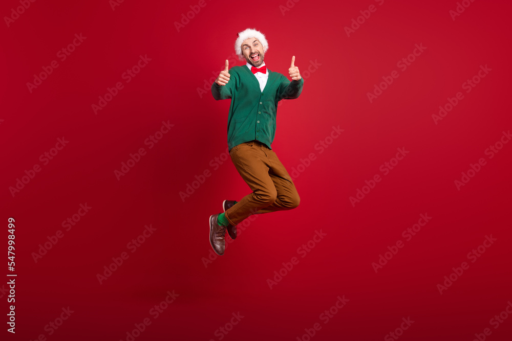 Full body portrait of overjoyed crazy guy jumping hands fingers show thumb up feedback isolated on red color background