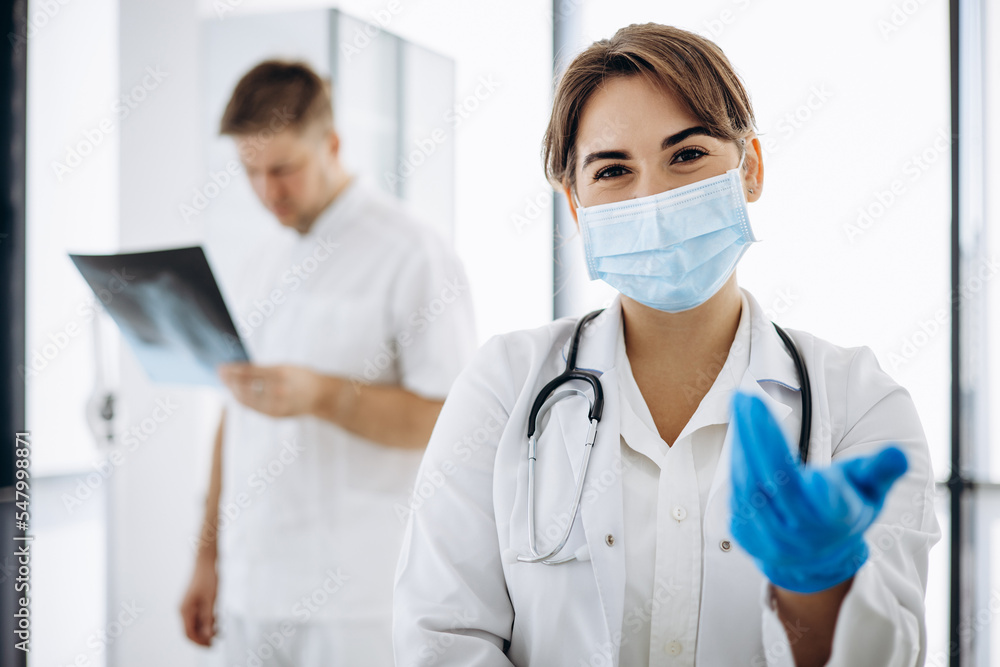 Colleagues standing in hospital holding x-ray and stethoscope Colleagues standing in hospital holding x-ray and stethoscope
