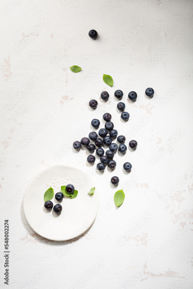 Overhead view of blueberry on small plate on light surface Overhead view of blueberry on small plate on light surface