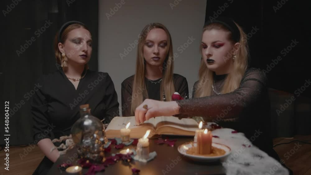 4K. Three female witches in a dark room insert needles into a voodoo doll 4K. Three female witches in a dark room insert needles into a voodoo doll