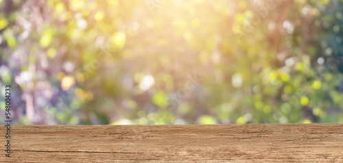 Wooden tabletop for product placement with a blury floral background. Place for displaying product mockups.