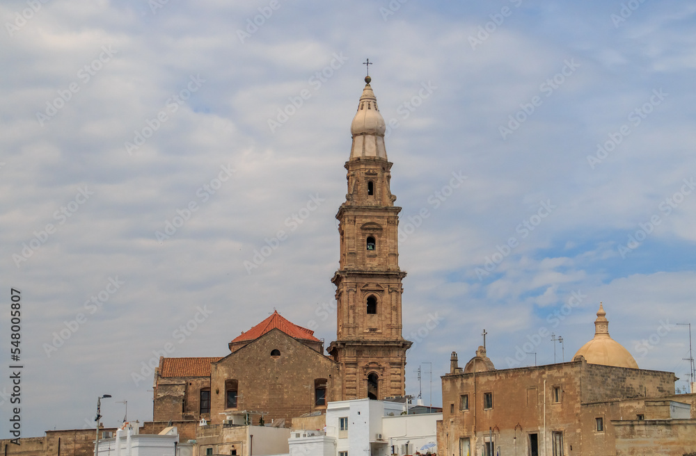 Campanario de la basílica Cattedrale Maria Santissima della Madia en Monopoli, Italia. El alto campanario con varias plantas destaca sobre el resto de edificios de la ciudad, foto en una mañana de ver Campanario de la basílica Cattedrale Maria Santissima della Madia en Monopoli, Italia. El alto campanario con varias plantas destaca sobre el resto de edificios de la ciudad, foto en una mañana de ver