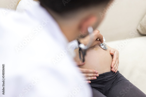 Cropped photo of doctor with stethoscope going to exam the pregnant woman.