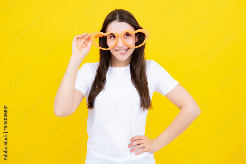 Girl with heart shaped glasses funny and smiling on yellow studio background. Girl with heart shaped glasses funny and smiling on yellow studio background.