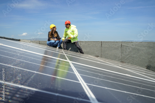 un ingegnere con l'operaio controllano la posa in opera dei pannelli fotovoltaici nel tetto di un edificio