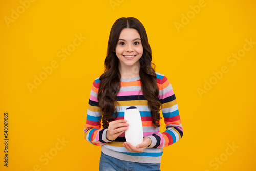 Teenage girl with shampoos conditioners or shower gel. Kids hair care cosmetic product, shampoo bottle. Happy teenager, positive and smiling emotions of teen girl.