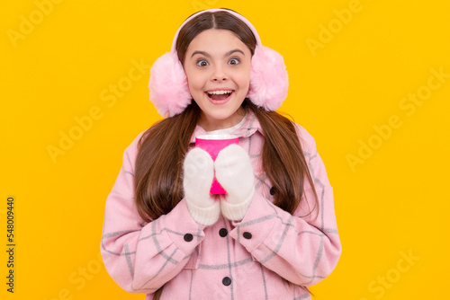 happy female fashion model on yellow background. teen girl in mittens with coffee cup.