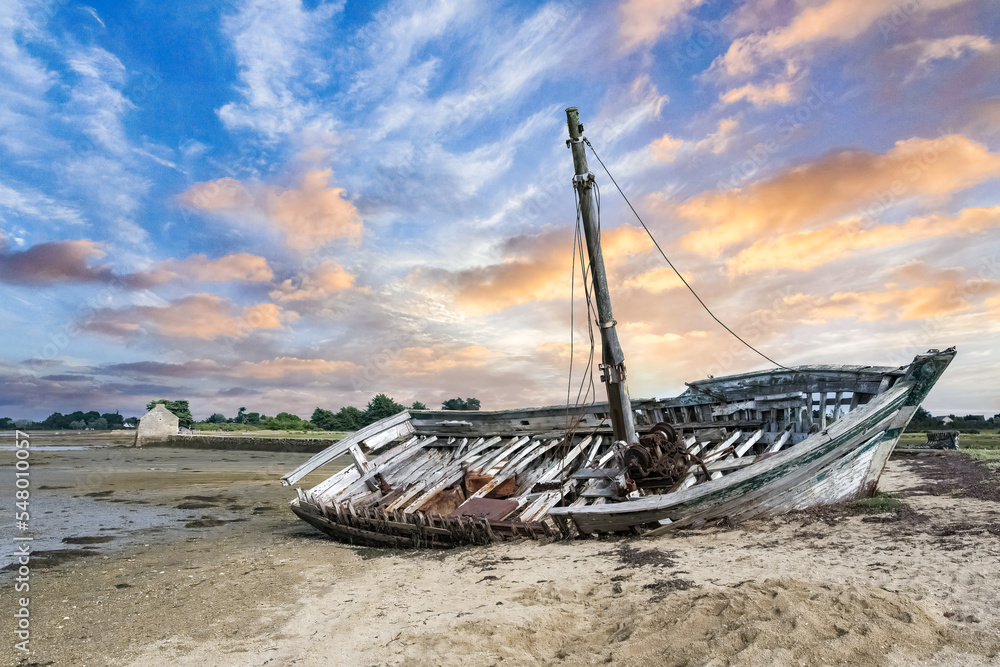 Brittany, Ile d’Arz in the Morbihan gulf, a wreck ship on the beach, with the traditional tide mill in background
