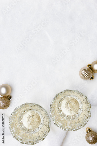 Holiday seasonal celebration concept, white sparkling wine in crystal glass, glasses champagne, Christmas balls white fur background. Minimal aesthetic design, new year holidays, top view