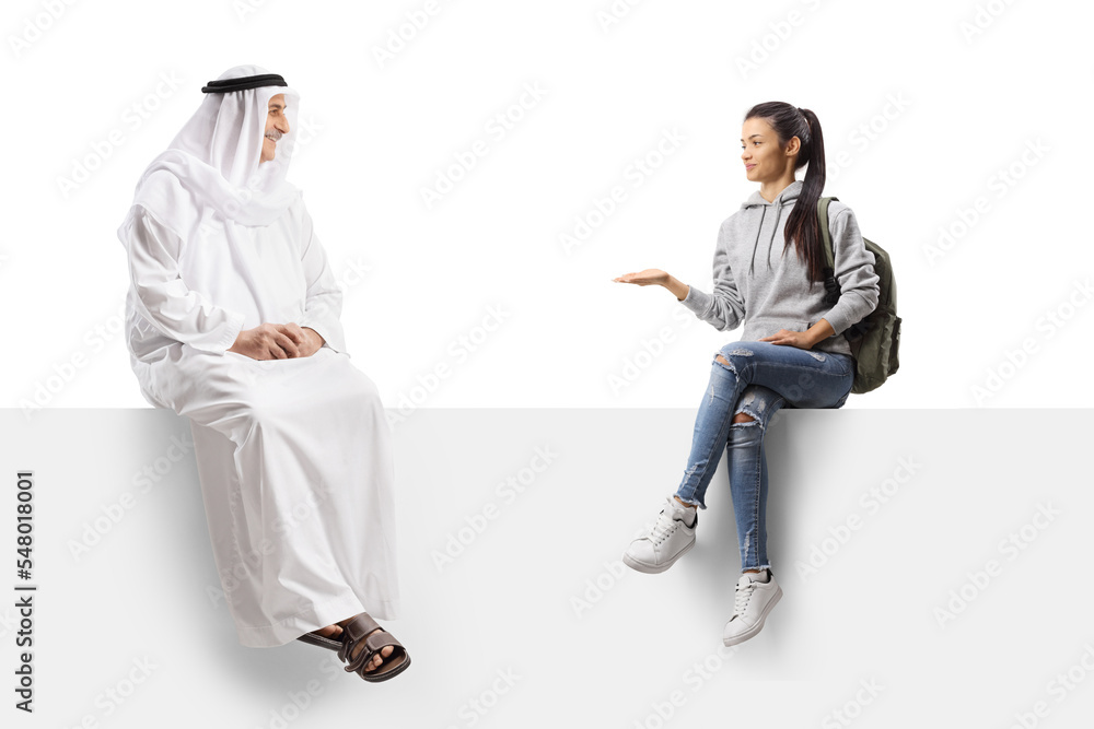 Female student sitting on a white board and talking to an arab man Female student sitting on a white board and talking to an arab man