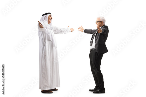 Full length profile shot of a mature arab man in a robe meeting a businessman friend