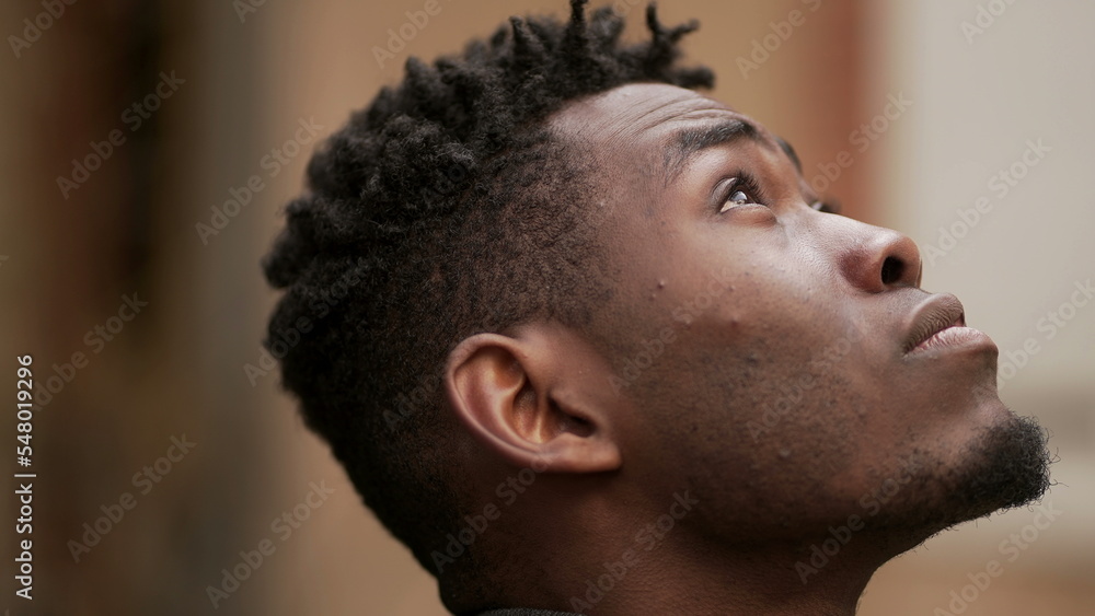 Obraz premium Pensive black African man standing outdoors thinking, looking up at sky in contemplation2