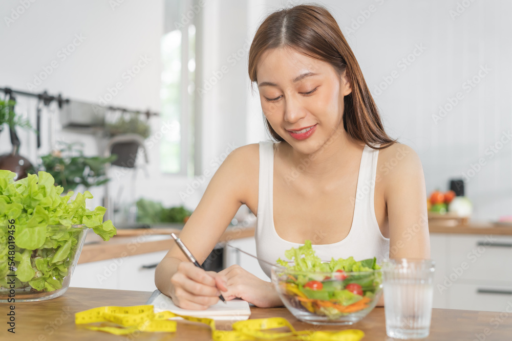 Diet, Dieting asian young woman working, write diet plan right nutrition, vegetables salad is food for good health not choose eat junk food. Nutritionist female, Weight loss person. Diet, Dieting asian young woman working, write diet plan right nutrition, vegetables salad is food for good health not choose eat junk food. Nutritionist female, Weight loss person.