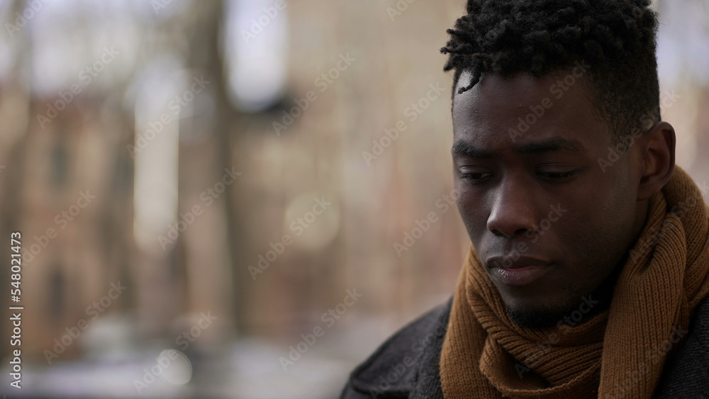 Pensive black African male walking outside in city while daydreaming alone Pensive black African male walking outside in city while daydreaming alone
