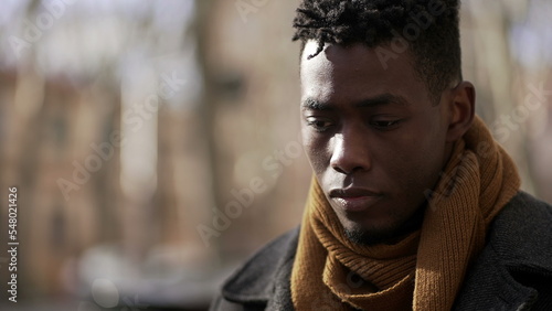 Obraz na płótnie Pensive black African male walking outside in city while daydreaming alone