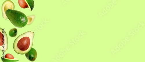 Background of juicy ripe avocados. Levitating avocados on a light green background