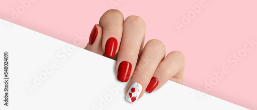 Manicured womans hand holding white paper. Fashionable valentines day nail design