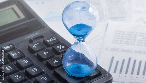 Best time for investment. Hourglass, financial charts and calculator.